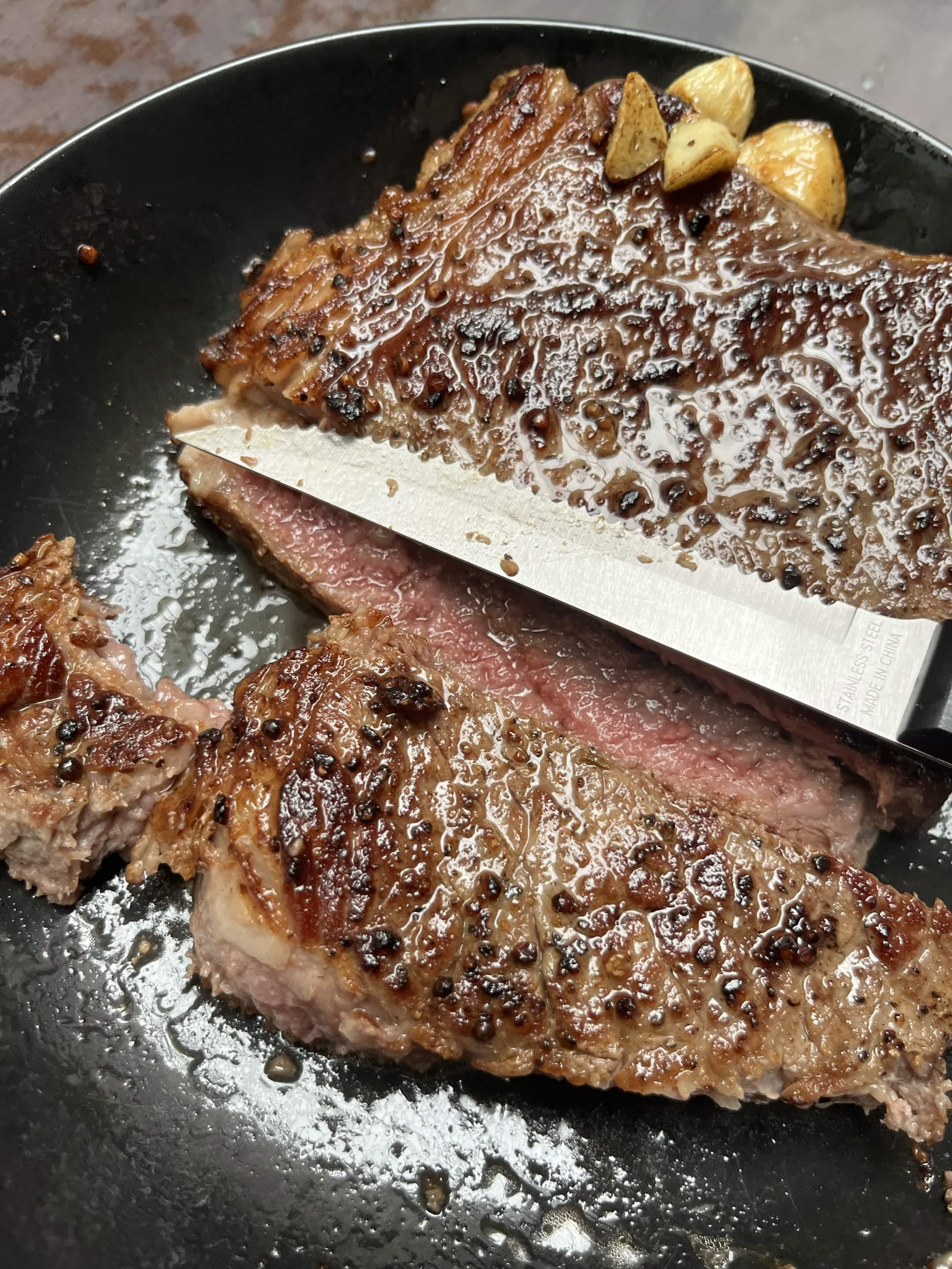 Sliced steak and potatoes on a black plate